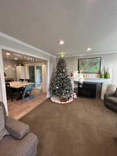 Carpeted living room with a tile fireplace, crown molding, and a textured ceiling