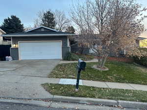 View of front of property with a garage and a yard