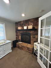 Living room with carpet flooring, a textured ceiling, and a fireplace