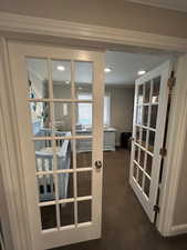 Doorway to outside featuring dark colored carpet, french doors, and ornamental molding