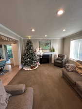 Living room featuring crown molding, a fireplace, carpet floors, and a textured ceiling