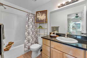 Full bathroom featuring shower / bathtub combination with curtain, lofted ceiling, toilet, vanity, and hardwood / wood-style flooring