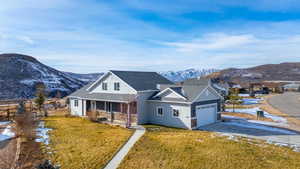 View of front of home with a mountain view, a front yard, and covered porch