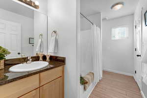 Bathroom with hardwood / wood-style floors, vanity, and shower / bath combination with curtain