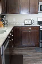 Kitchen with light stone counters, dark brown cabinets, and stainless steel appliances