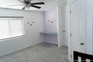 Carpeted bedroom featuring ceiling fan