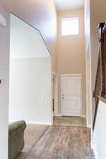 Entryway with hardwood / wood-style floors and a towering ceiling