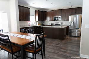 Kitchen with a center island, dark hardwood / wood-style flooring, dark brown cabinetry, and appliances with stainless steel finishes