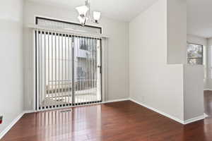 Unfurnished room featuring dark hardwood / wood-style flooring and an inviting chandelier