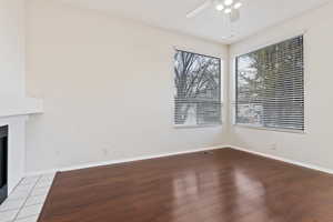 Interior space featuring ceiling fan, wood-type flooring, and a tiled fireplace