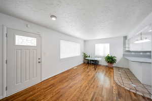 Foyer entrance featuring hardwood / wood-style flooring, a healthy amount of sunlight, and a textured ceiling