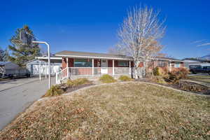 Single story home featuring an outdoor structure, covered porch, a front yard, and a garage