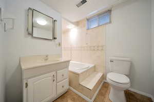 Bathroom with tile patterned floors, vanity, toilet, and a bath