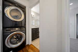 Washroom with stacked washer / dryer and dark wood-type flooring