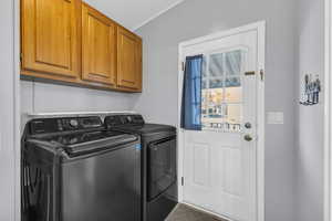 Washroom with cabinets, separate washer and dryer, and crown molding