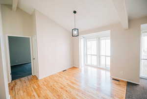 Interior space with lofted ceiling with beams, plenty of natural light, and wood-type flooring