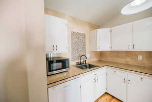 Kitchen featuring dishwasher, white cabinets, and sink