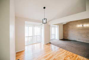 Empty room with hardwood / wood-style floors, wooden walls, and a chandelier