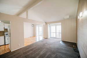 Unfurnished living room with light wood-type flooring and lofted ceiling with beams