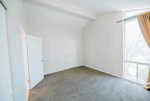 Unfurnished room with vaulted ceiling with beams, carpet floors, and a wealth of natural light