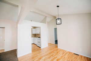 Interior space with beam ceiling, light hardwood / wood-style flooring, and high vaulted ceiling