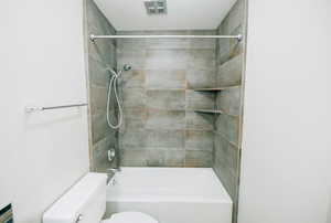 Bathroom with tiled shower / bath combo and toilet