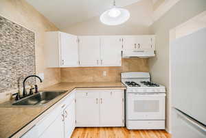 Kitchen featuring white appliances, white cabinets, sink, light hardwood / wood-style flooring, and decorative light fixtures