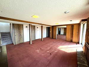 Interior space featuring carpet flooring, wood walls, and a textured ceiling