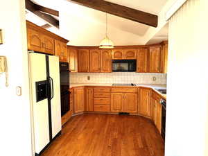 Kitchen featuring decorative backsplash, vaulted ceiling with beams, hanging light fixtures, and black appliances