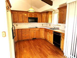 Kitchen featuring black appliances, lofted ceiling with beams, sink, decorative backsplash, and dark hardwood / wood-style flooring