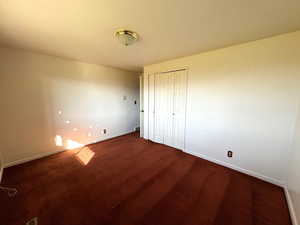 Unfurnished bedroom with dark carpet and a closet