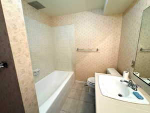 Bathroom with tile patterned flooring, vanity, toilet, and a washtub