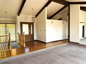 Foyer with beam ceiling, hardwood / wood-style floors, high vaulted ceiling, and a chandelier