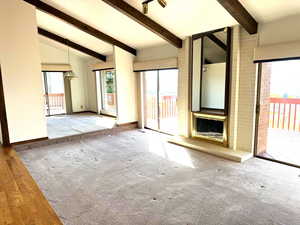 Unfurnished living room with hardwood / wood-style floors, lofted ceiling with beams, and a notable chandelier