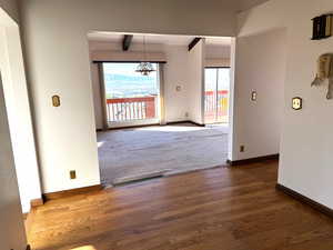 Unfurnished dining area featuring beam ceiling and dark hardwood / wood-style flooring