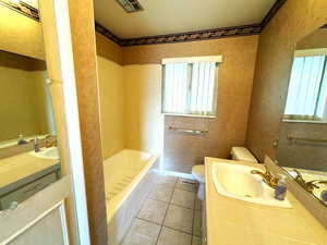 Bathroom with tile patterned floors, a tub, vanity, and toilet