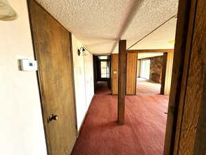 Corridor with carpet and a textured ceiling