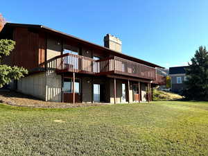 Back of house featuring a deck and a lawn