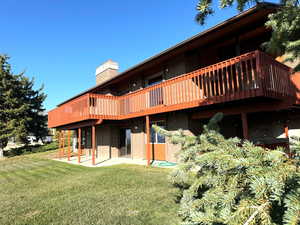 Rear view of property with a lawn and a patio area