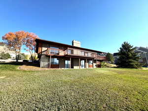 Back of house with a deck and a yard