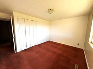 Unfurnished bedroom with dark colored carpet and a closet