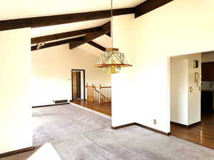 Spare room with hardwood / wood-style floors, high vaulted ceiling, an inviting chandelier, and beam ceiling