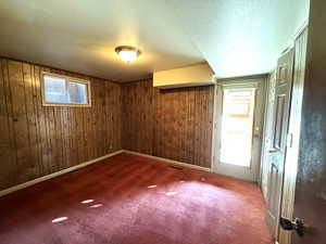 Carpeted spare room featuring a textured ceiling and wooden walls