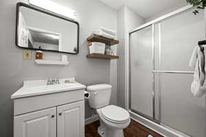 Bathroom featuring hardwood / wood-style floors, vanity, toilet, and an enclosed shower