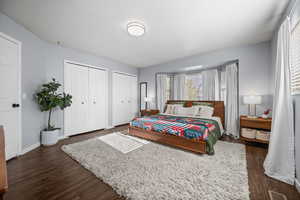 Bedroom with dark hardwood / wood-style flooring and two closets