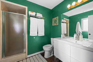 Bathroom featuring wood-type flooring, vanity, toilet, and walk in shower