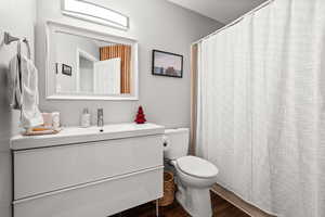 Bathroom featuring curtained shower, toilet, vanity, and hardwood / wood-style flooring