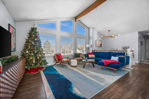 Living room featuring hardwood / wood-style floors, beamed ceiling, high vaulted ceiling, and a notable chandelier