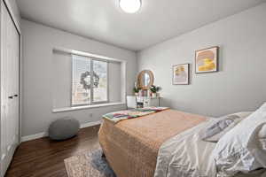 Bedroom with dark hardwood / wood-style floors and a closet