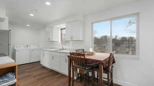 Kitchen featuring separate washer and dryer, sink, white cabinets, and dark wood-type flooring